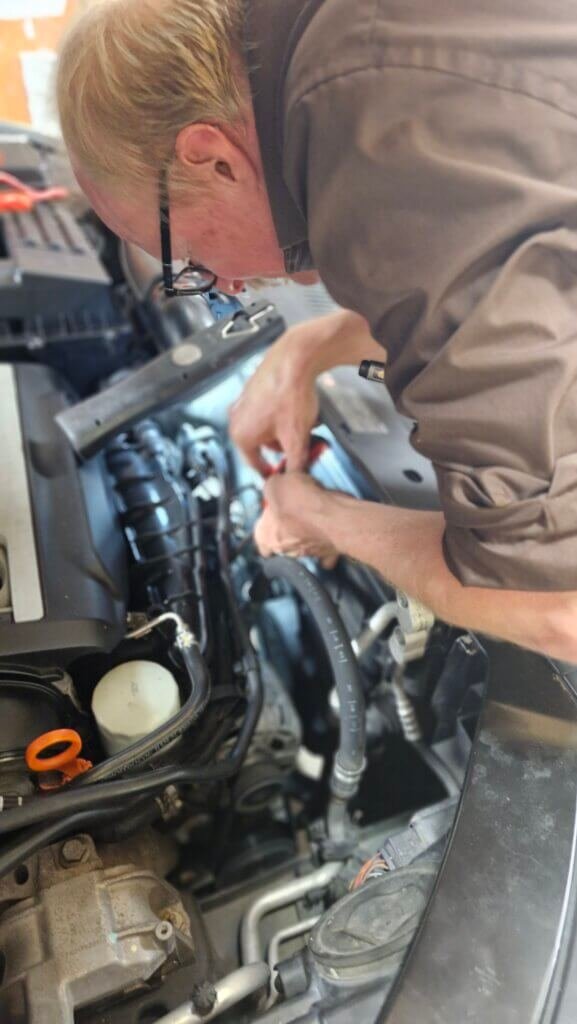A mechanic bends over the front of an engine.